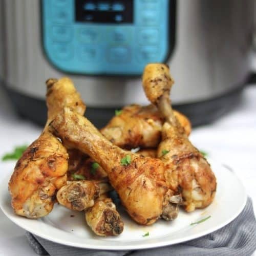 Instant pot chicken drumsticks served on plate and placed in front of the instant pot