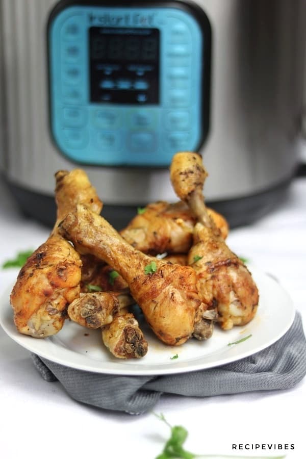 Instant pot chicken drumsticks served on plate and placed in front of the instant pot
