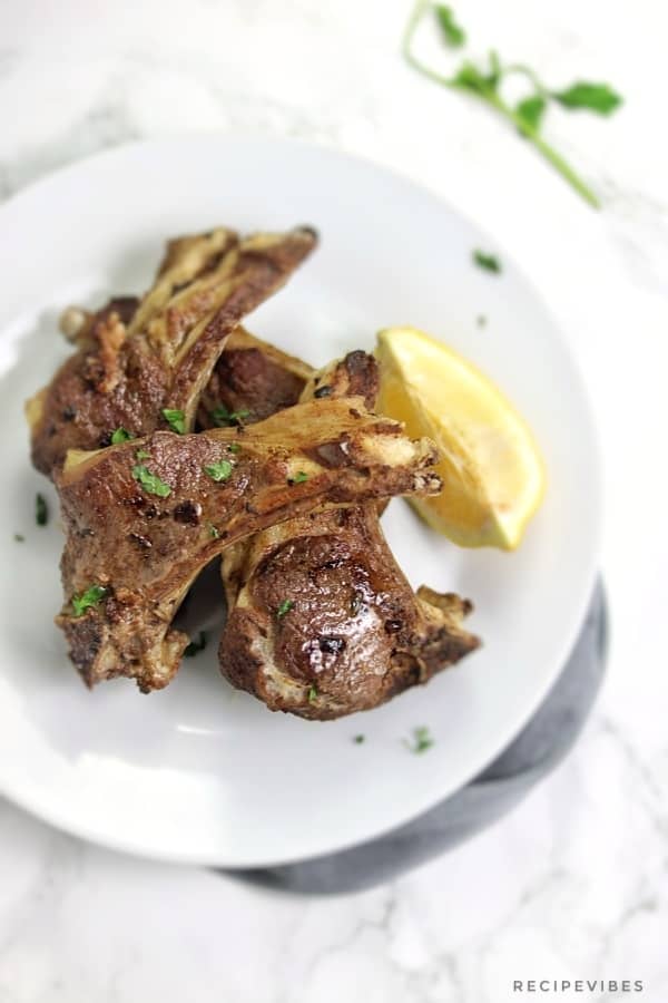 Instant pot lamb chops served on white plate and garnished with lemon