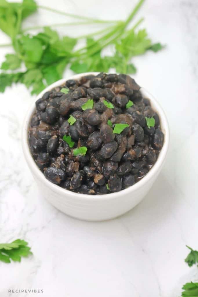 instant pot black beans in white bowl garnished with coriander