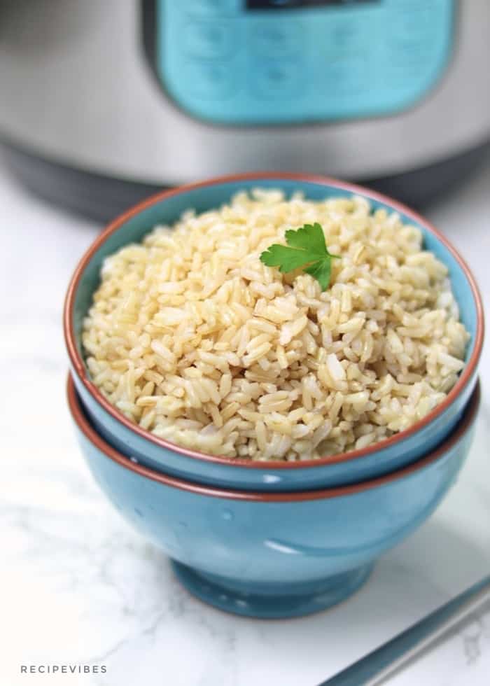 cooked brown rice served in a bowl with instant pot at the background