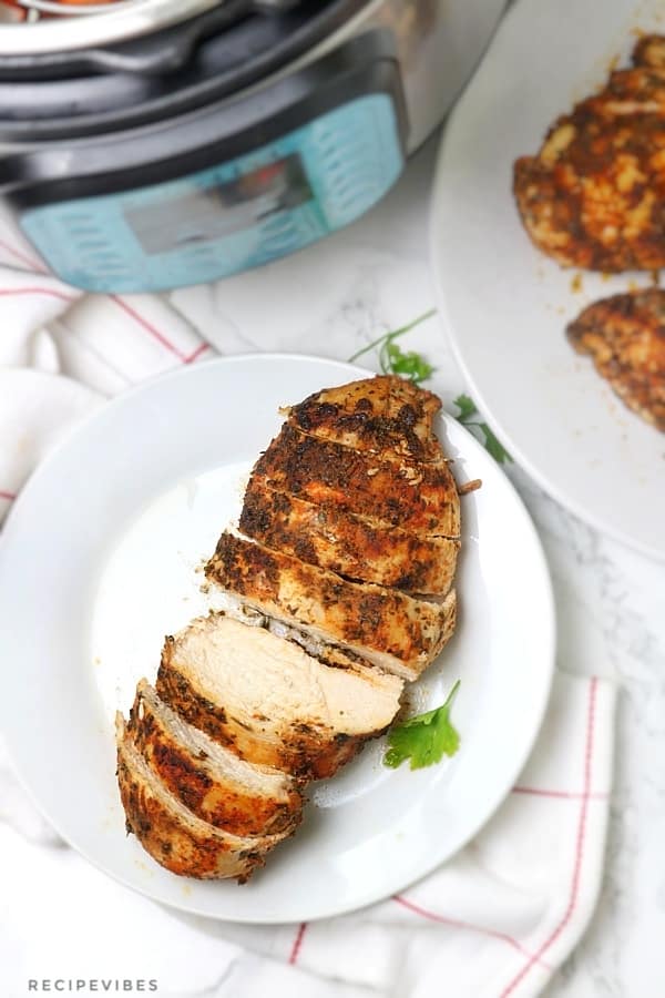 Instant pot chicken breast served on plate with instant pot showing in the picture backgroung