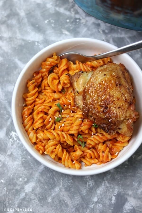 instant pot pasta with a side of chicken thighs served in white plate