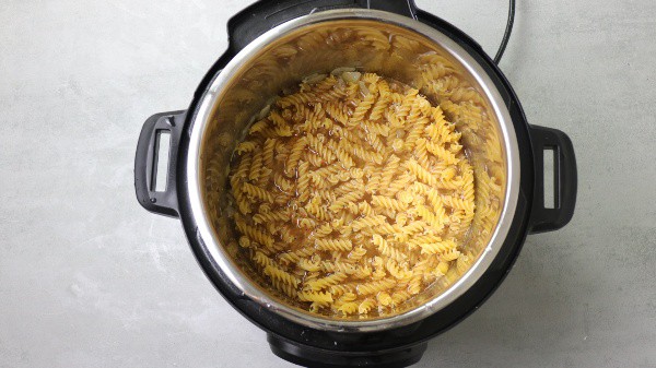 fusili pasta in the instant pot covered with chicken broth