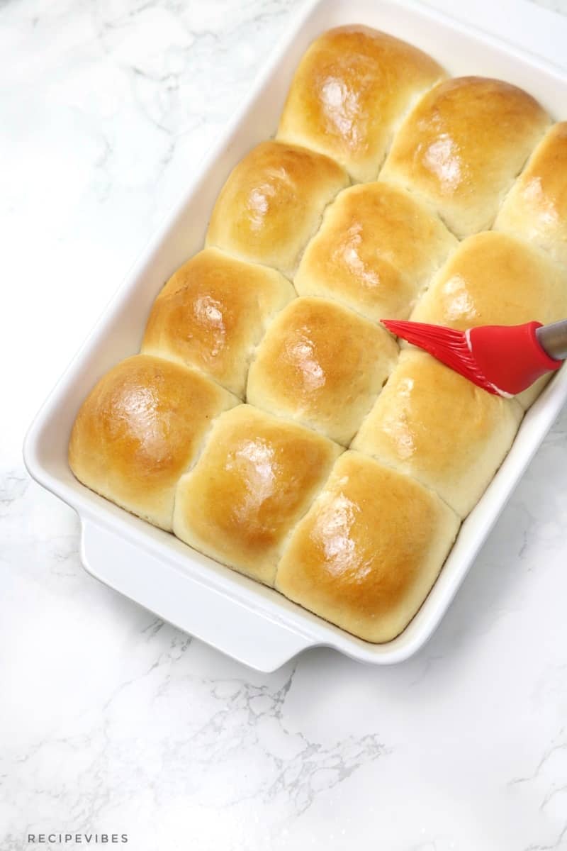Bread rolls inside oven dish brushed with butter