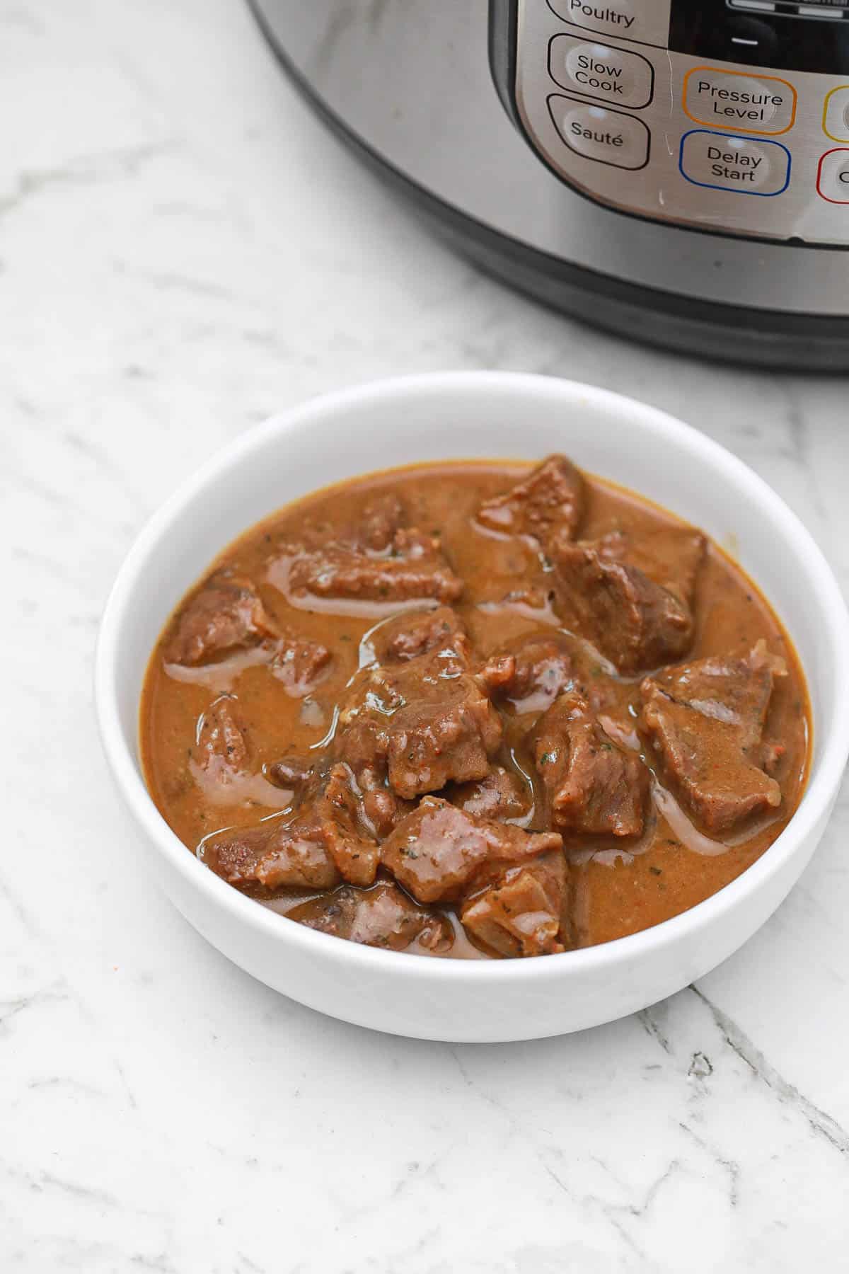 Instant pot beef tips and gravy in a white plate.