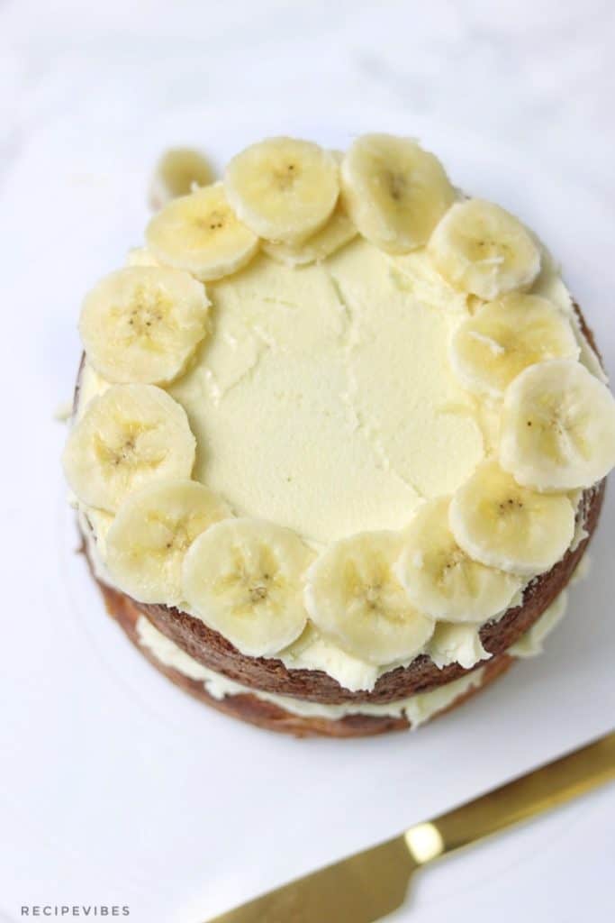 frosted banana cake topped with sliced bananas