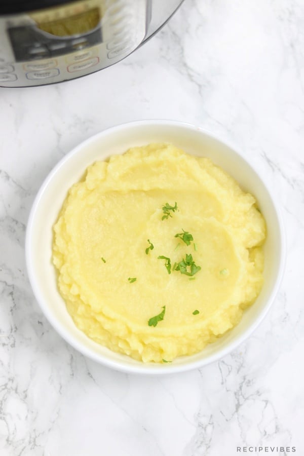 Creamy mashed potatoes served in a plate and displayed in front of instant pot