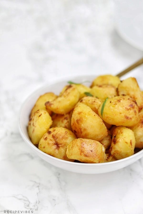 the roast potatoes served in a bowl. they look crispy 