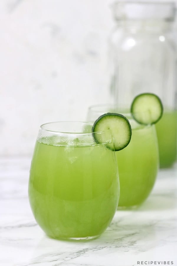 cucumber juice in 2 glass cups and a pitcher half full.