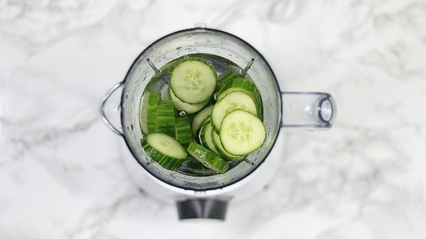 sliced cucumbers and water inside a blender.