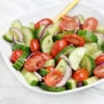 cucumber tomato salad served on white plate