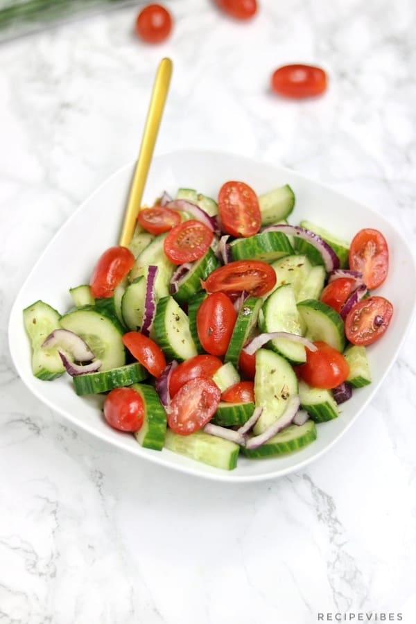 picture showing a bowl of cucumber tomato salad with left overtomatoes in the background