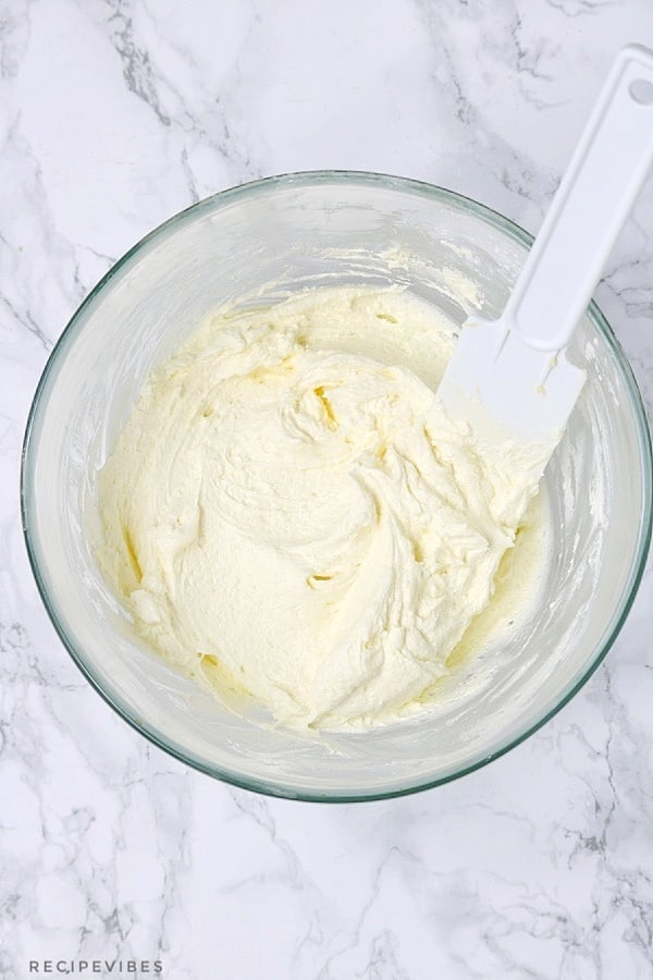 buttercream frosting inside a bowl with white spatula.