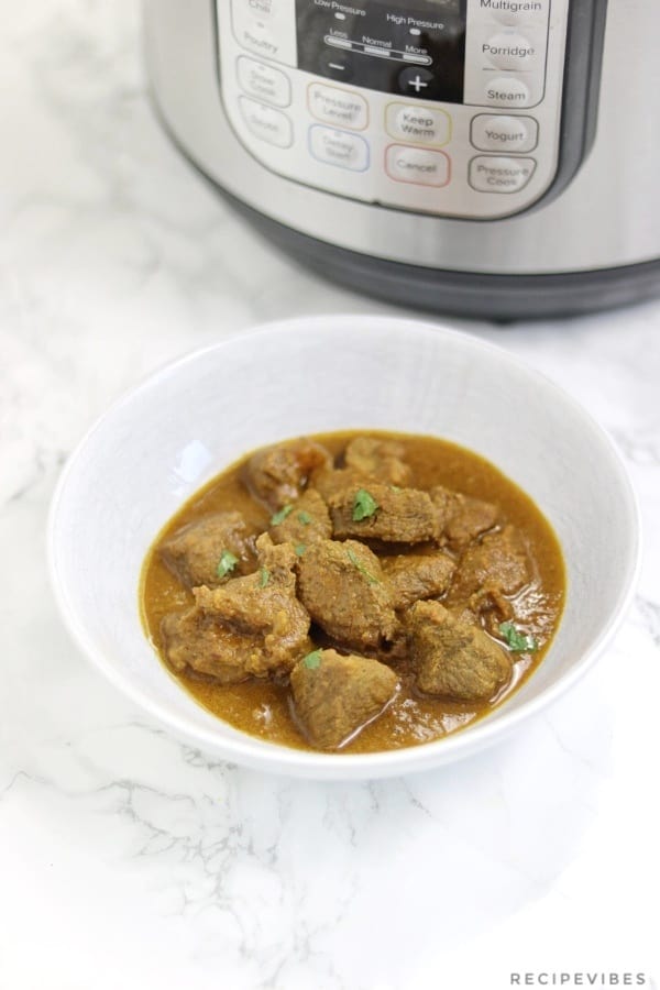 beef curry in bowl displayed infront of instant pot