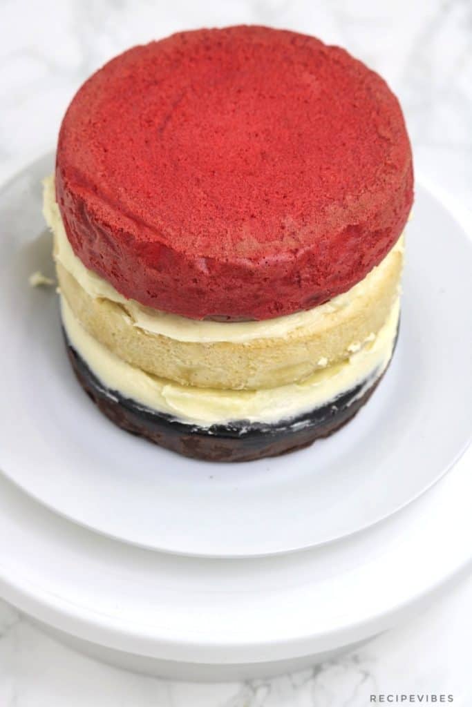 instant pot chocolate , red velvet and vanilla cake stacked on one another.