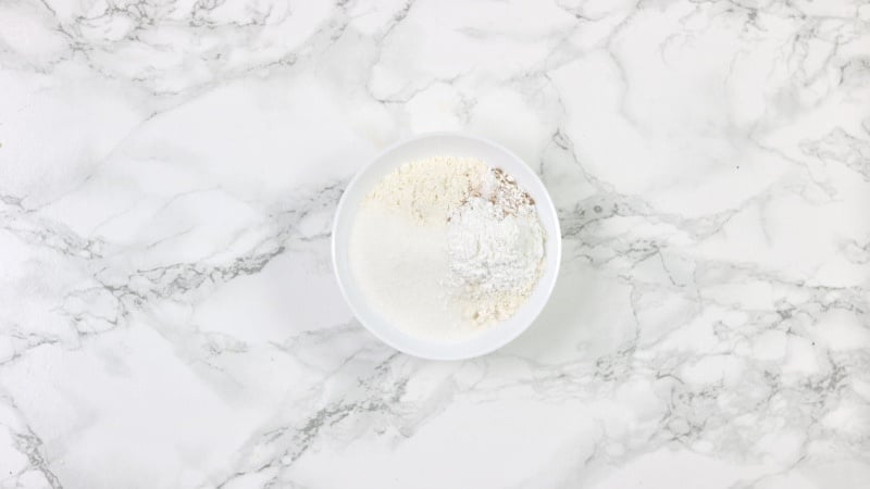 flour, nutmeg, sugar, baking powder and sugar in a white bowl.