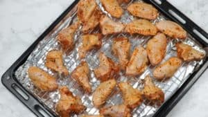 marinated wings arranged on rack on oven tray.