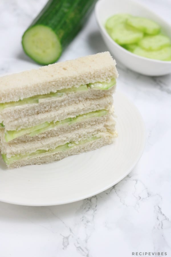 cucumber sandqiches stacked on a cream plate.