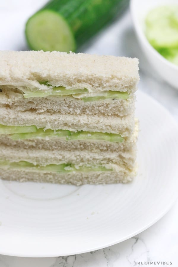 the sandwiches on a plate with cucumber in the background.
