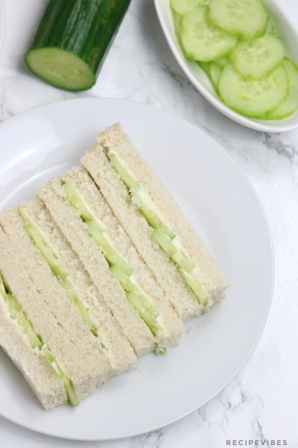 the sandwiches on a white plate with half a cucumber and sliced cucumbers in background.