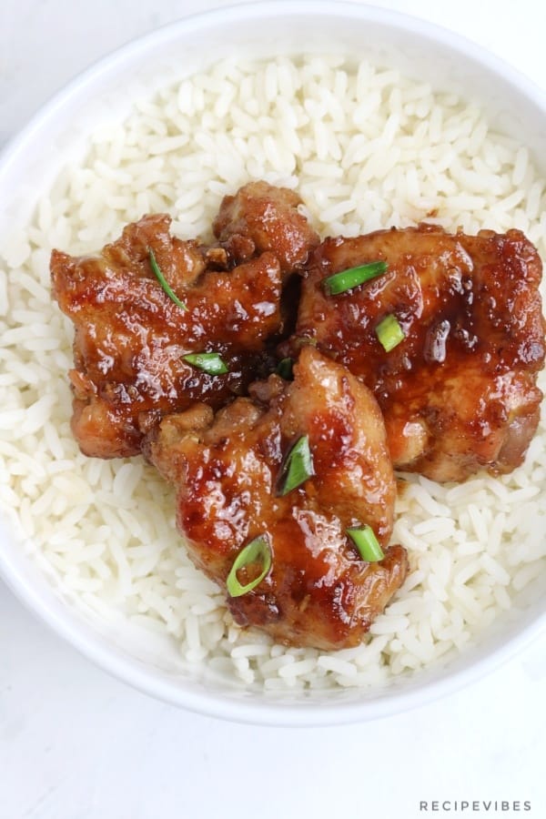 honey garlic chicken served on rice and garnished with spring onions.