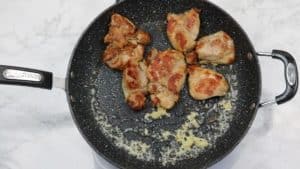 garlic and pan fried chicken in skillet.