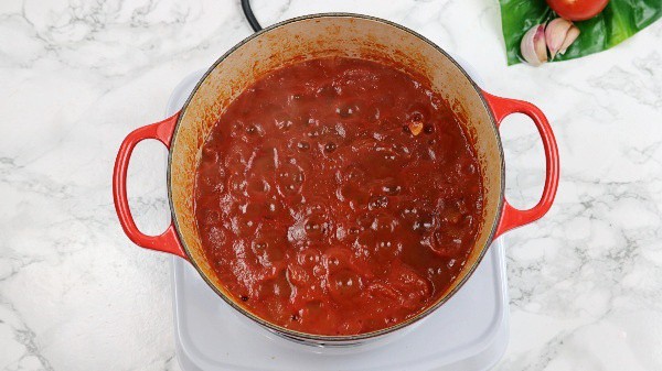 marinara sauce in a red pot on hot plate.