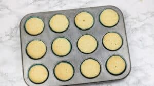12 vanilla cupcakes in muffin pan.