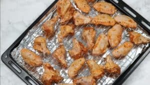 Marinated wings arranged on oven tray.
