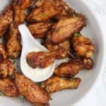 Honey soy chicken wings in a plate with one wing dipped in ranch sauce.