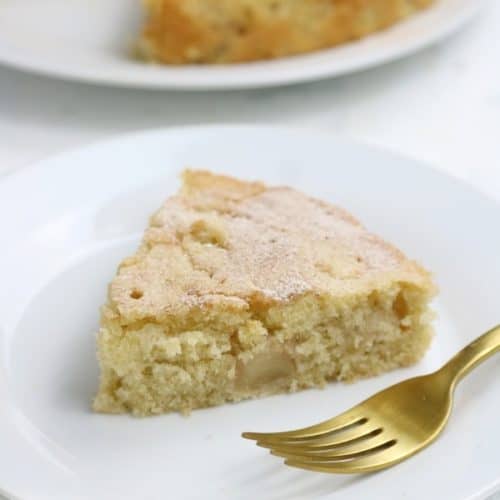 Slice of Apple cake on a white plate with gold fork.