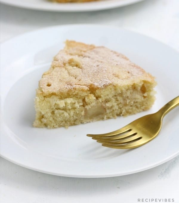 Apple cake slice with gold fork on the plate.