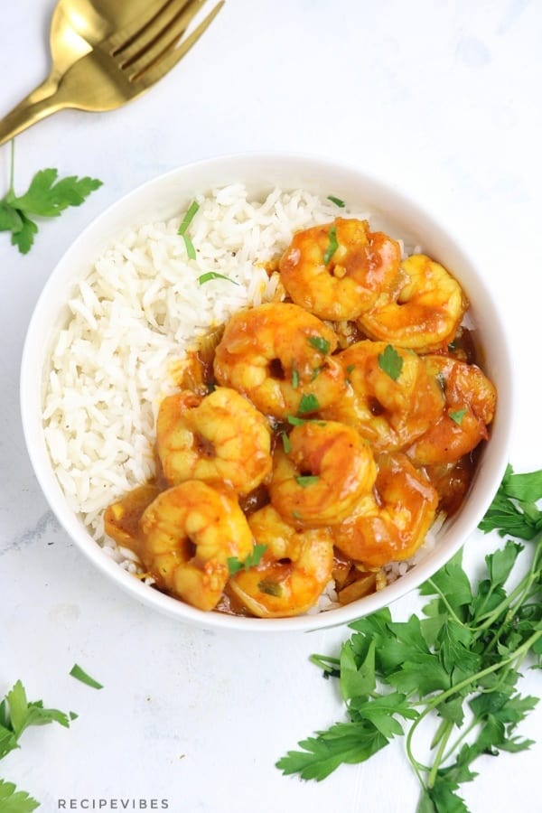 shrimp curry served over rice in a white plate.