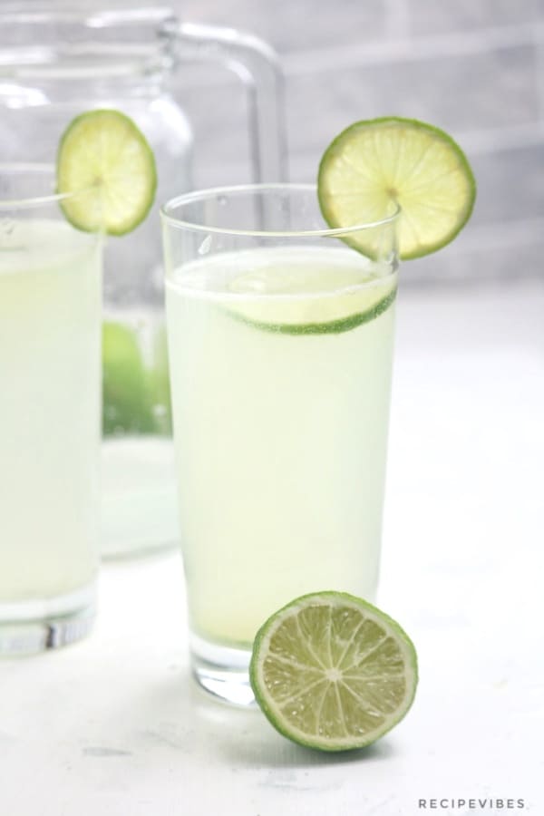 Lime juice in a glass cup garnished with a slice of lime.
