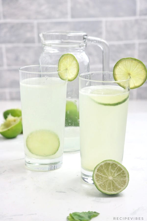 lime juice in 2 glass cups and a pitcher.