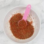 Steak seasoning scooped with pink spoon in a white bowl