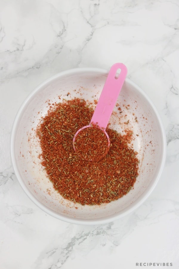 Steak seasoning scooped with pink spoon in a white bowl