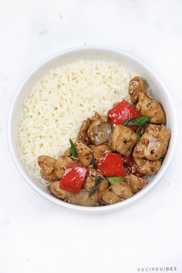 Black pepper chicken stir fry and rice served in a white bowl.