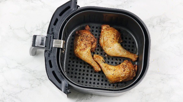 cooked chicken in air fryer basket.
