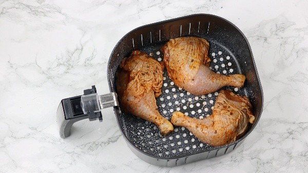 marinated chicken legs arranged in the air fryer basket.