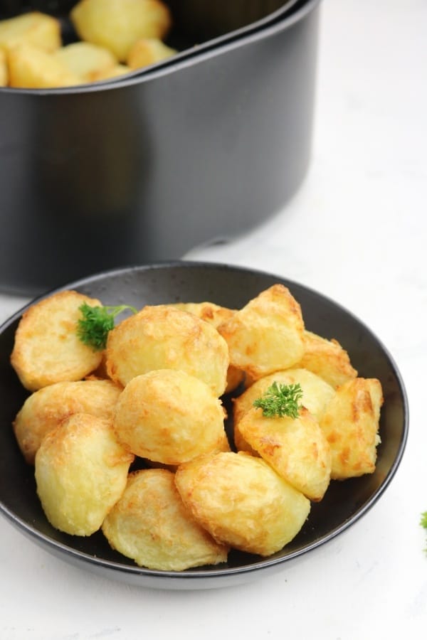 air fryer potatoes garnished with parsley in a black plate.