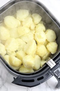Potatoes in air fryer basket.