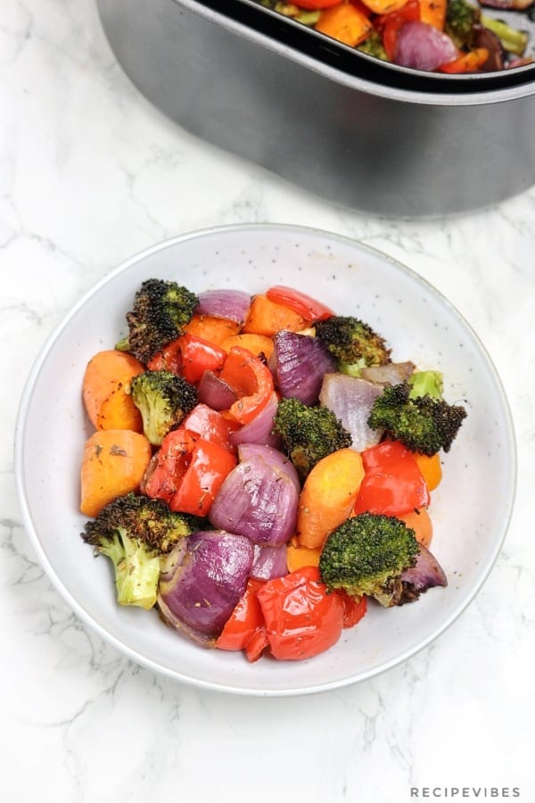 air fryer roasted vegetables in fryer baket and on a plate.
