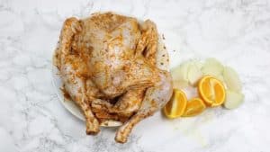 The marinated bird with quartered onion and orange beside it.