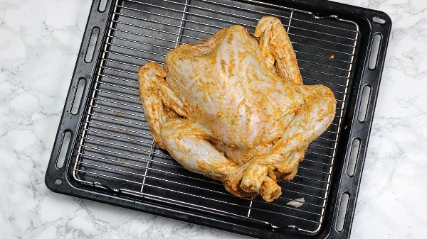 marinated turkey on rack placed over roasting tray.
