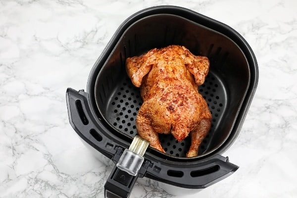 marinated chicken breast side down in air fryer basket.