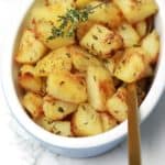 Roasted cubed potatoes served with a spoon for dishing in the plate.