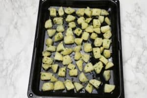 the seasoned potatoes on a baking tray.