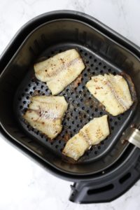 cooked fish inside air fryer baskets.